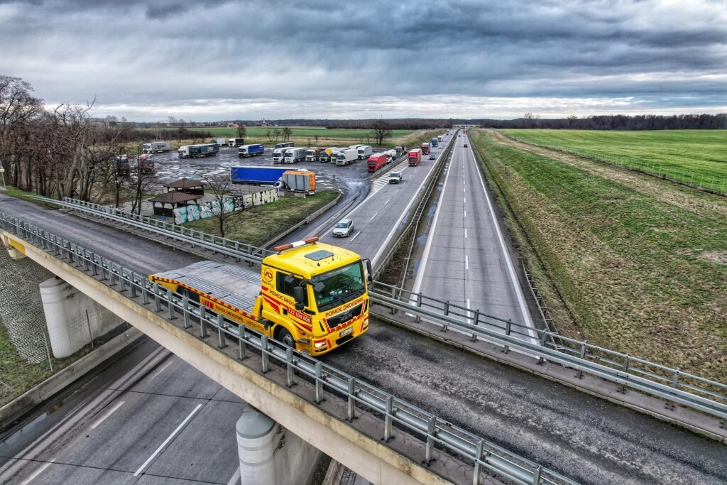 Laweta Legnica przewożąca samochód SUV na platformie transportowej podczas pomocy drogowej po awarii auta.